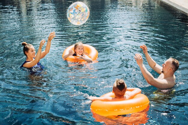 Família feliz com dois filhos se divertindo na piscina conceito de férias de verão