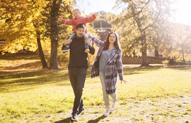 Família feliz com filha no parque outono recreação ao ar livre