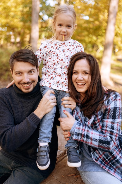 Família feliz com filha no parque outono recreação ao ar livre