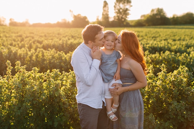 Família feliz com filha passar algum tempo juntos no campo ensolarado