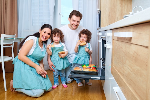 Família feliz com filhas gêmeas na cozinha alegre mãe pai duas filhas gêmeas preparando comida na cozinha o conceito de uma família feliz