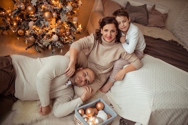 família feliz com filho debaixo da árvore de natal no quarto