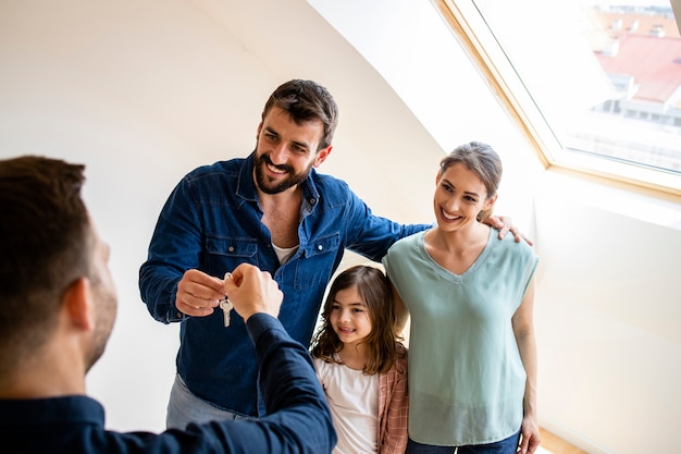 família feliz com filhos comprando um imóvel ou recebendo as chaves da nova casa de um agente imobiliário