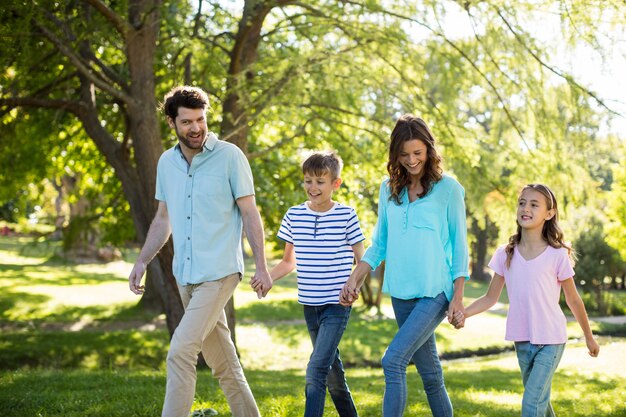 Família feliz com mãos dadas andando no parque