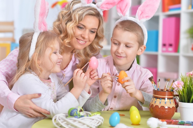 Família feliz com orelhas de coelho se preparando para a Páscoa e os ovos de cor.