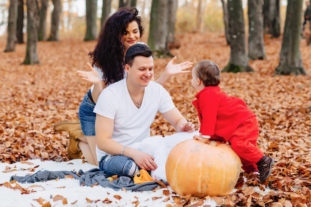 Família feliz, com, pequeno, cute, criança, parque, ligado, folha amarela, com, grande, abóbora, em, outono