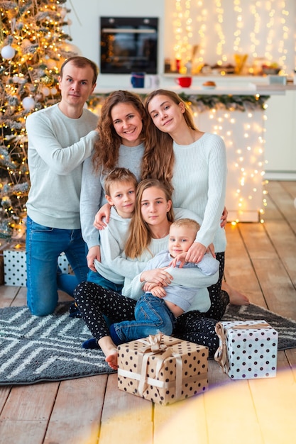 Família feliz com quatro sibilings perto da árvore de Natal com as caixas de presentes. Manhã de Natal em família, conceito de clima de Natal