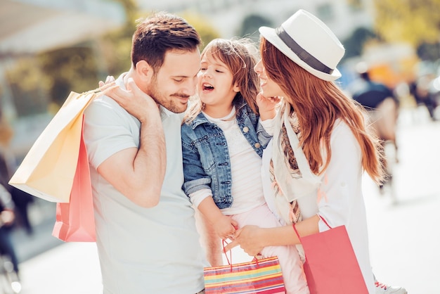 Família feliz com sacolas de compras na cidade