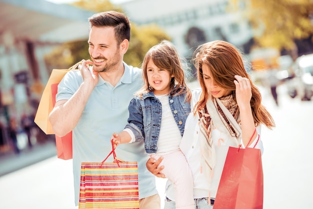 Família feliz com sacolas de compras na rua