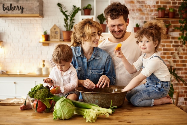 Família feliz com seus filhos cozinhando na cozinha