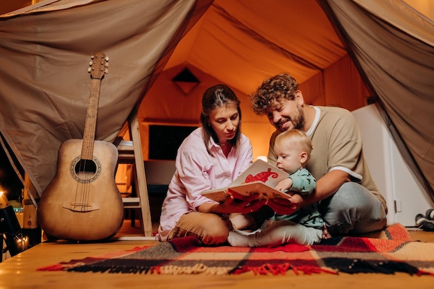 Família feliz com um bebê adorável brincando e passando tempo juntos em glamping na noite de verão Barraca de acampamento de luxo para recreação ao ar livre e recreação Conceito de estilo de vida