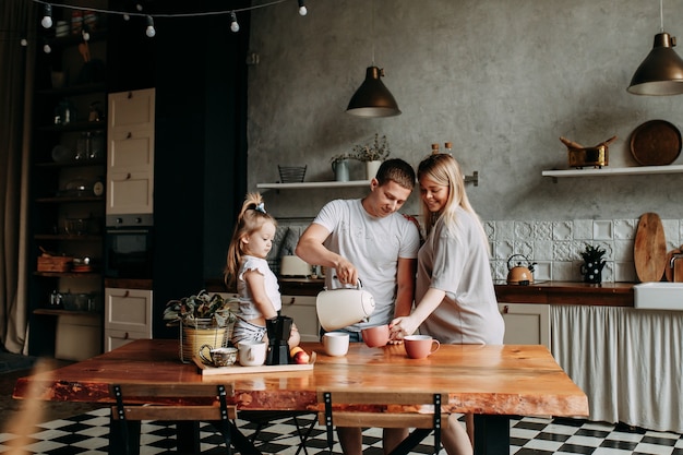 Família feliz com uma criança cozinha e ri na cozinha