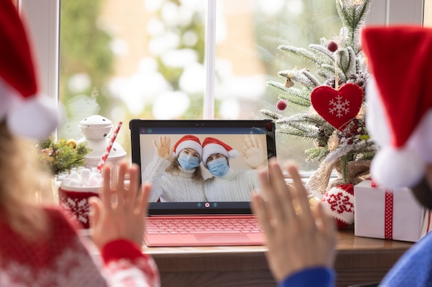 Família feliz comemorando o feriado de Natal online por bate-papo por vídeo em quarentena. Conceito de ficar em casa de bloqueio. Festa de Natal durante o coronavírus pandêmico COVID 19