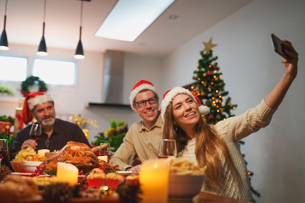 Família feliz comemorando o jantar de Natal e tirando selfie junto com os avós em casa