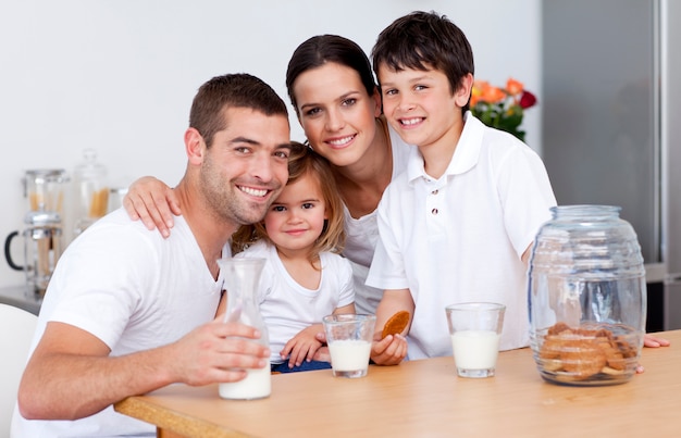 Família feliz comendo biscoitos e bebendo leite