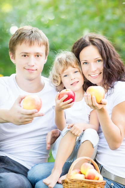 Família feliz comendo frutas ao ar livre no parque primavera contra fundo verde Conceito de estilo de vida saudável