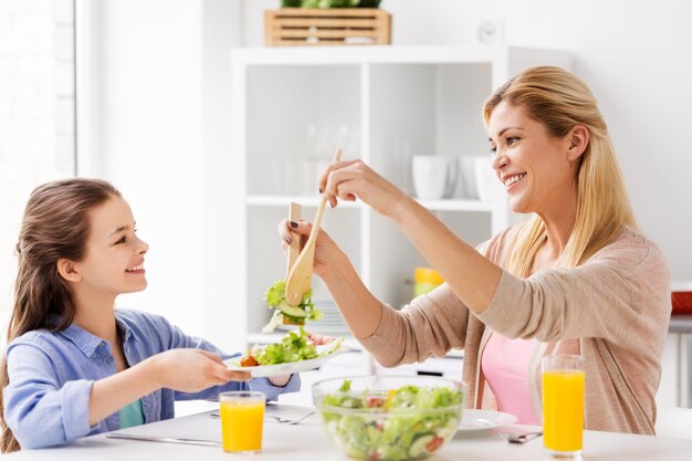 familia feliz comiendo ensalada en la cocina de casa