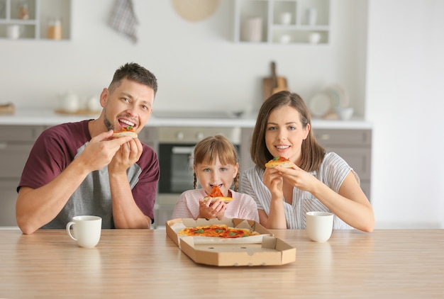 Foto familia feliz comiendo pizza en casa