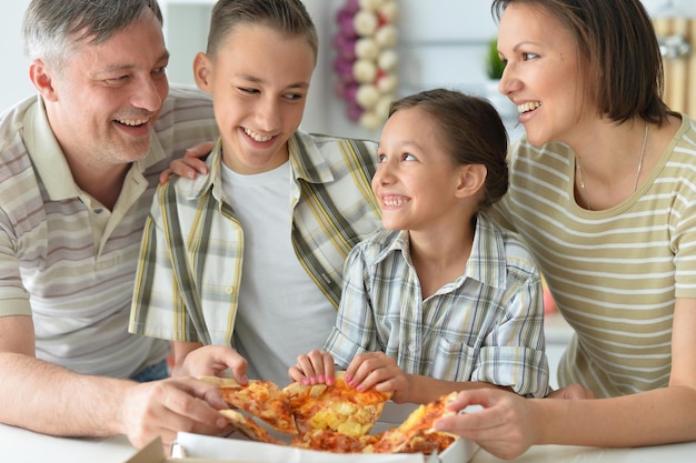 Familia feliz comiendo pizza juntos en el parque de otoño