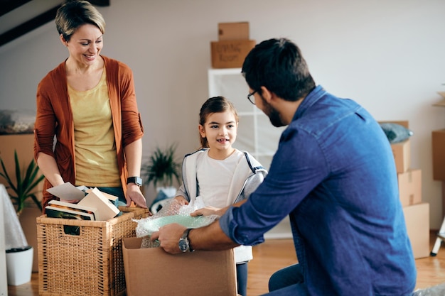 Familia feliz comunicándose mientras desempaca cajas de cartón en su nuevo hogar