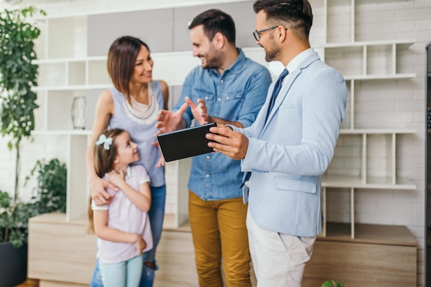 Família feliz conversando com agente imobiliário sobre a compra de uma nova casa.