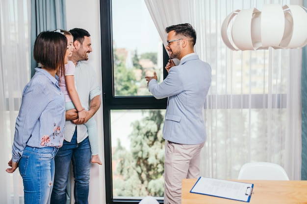 Família feliz conversando com agente imobiliário sobre a compra de uma nova casa.