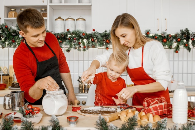 Família feliz cozinhando biscoitos de Natal na cozinha. Crianças cozinhando com os pais