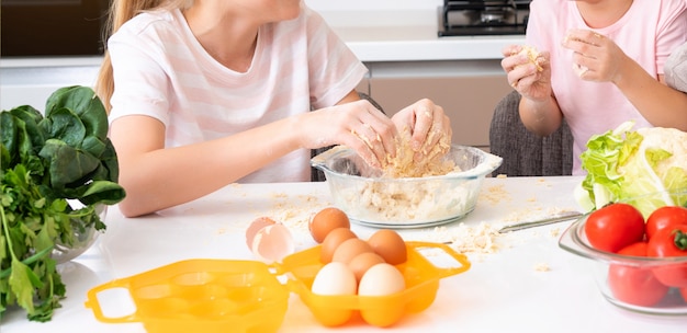 Família feliz crianças engraçadas estão preparando a massa, assar biscoitos na cozinha. irmãs se divertindo juntos rindo