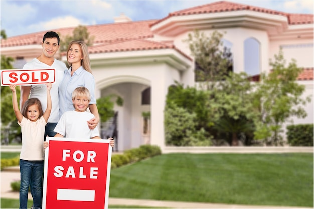 Familia feliz de cuatro con cartel de venta