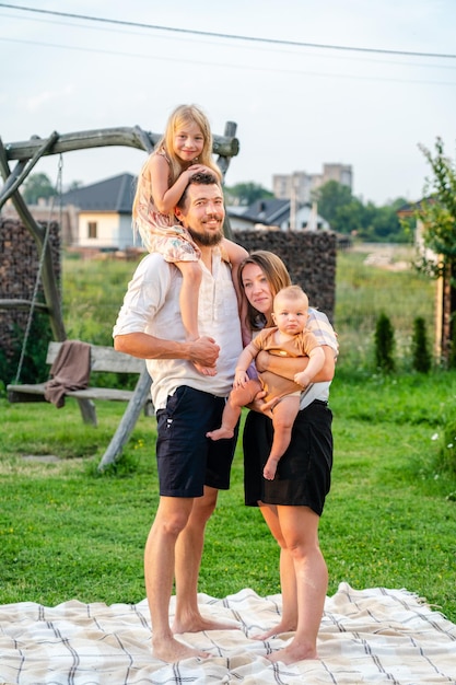 Familia feliz de cuatro divirtiéndose juntos descansando sobre una manta en verano