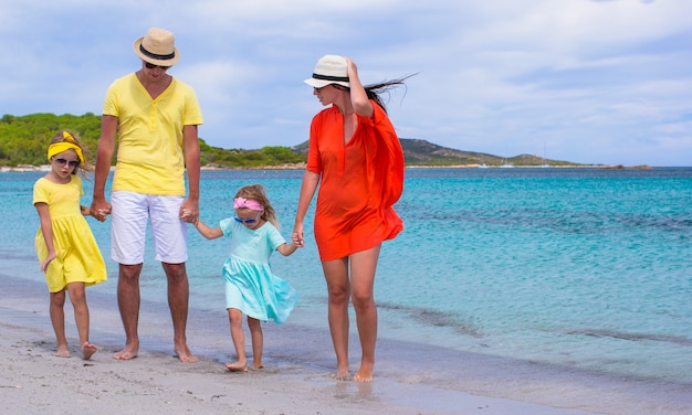 Familia feliz de cuatro en vacaciones en la playa