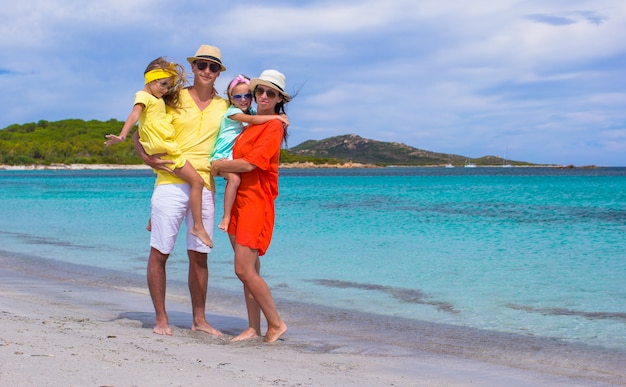 Familia feliz de cuatro en vacaciones en la playa