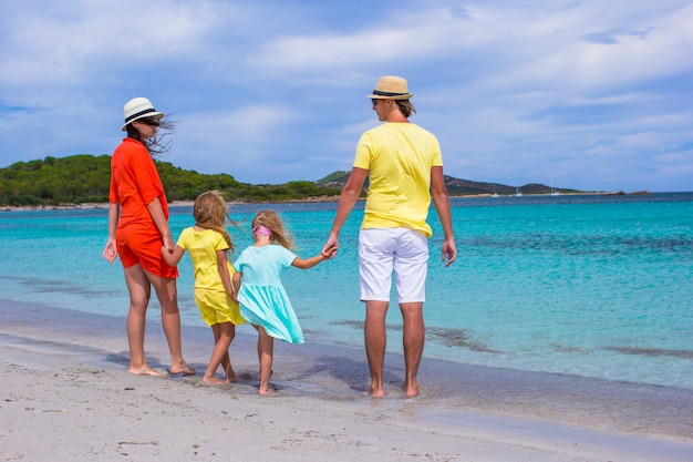 Familia feliz de cuatro en vacaciones en la playa