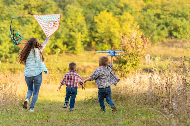 Família feliz da jovem mãe e seus filhos, lançando uma pipa na natureza