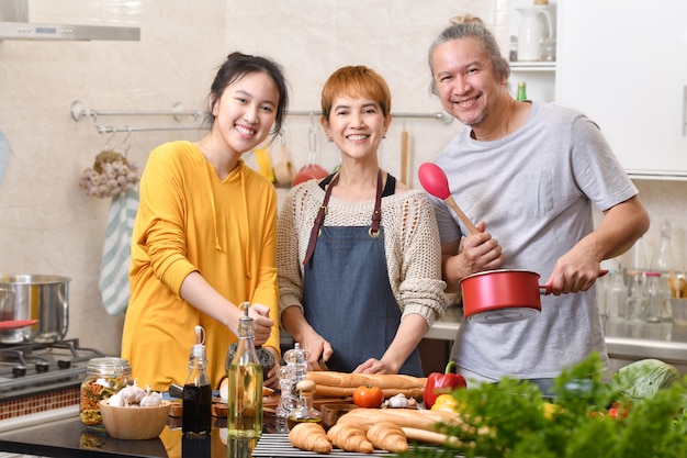 Família feliz da mãe pai e filha cozinhando na cozinha, fazendo comida saudável, se divertindo