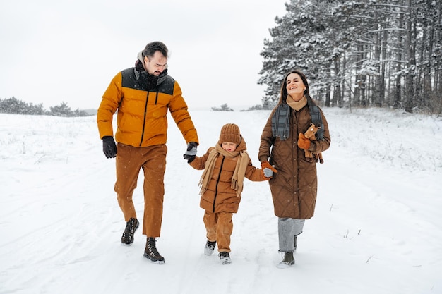 Familia feliz dando un paseo en invierno al aire libre en el bosque de nieve
