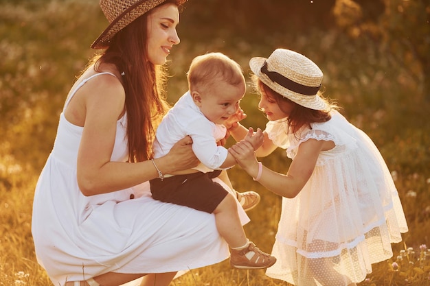 Família feliz de mãe filho e filha passando tempo livre no campo na hora do dia ensolarado de verão