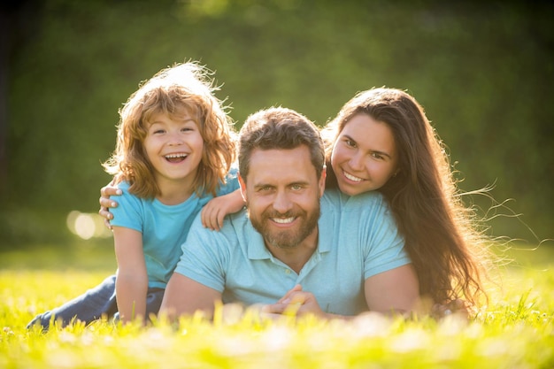 Família feliz de mãe pai e filho filho relaxando na grama verde do parque de verão, paternidade