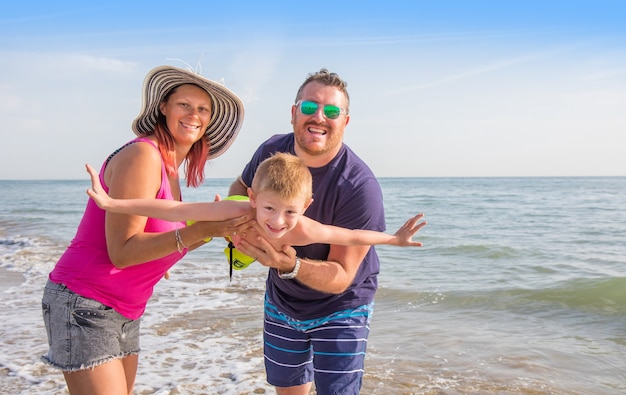 Família feliz de mãos dadas com um menino na praia