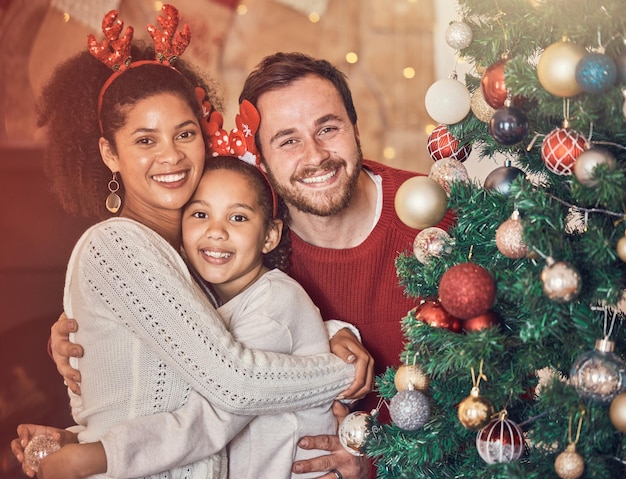 Foto família feliz de natal e retrato em casa se abraçam e se unem sorriso de natal e rosto dos pais com menina criança interracial e mãe africana abraçam o pai para celebração de festa e feriado