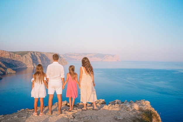 Família feliz de quatro andando nas montanhas na sunset