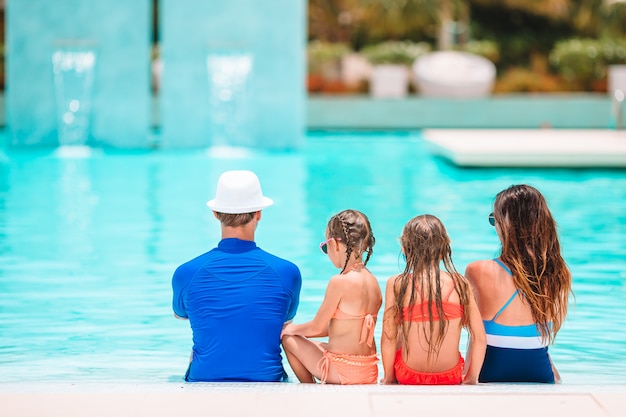 Família feliz de quatro na piscina ao ar livre