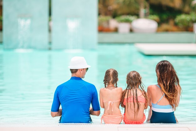 Família feliz de quatro na piscina ao ar livre