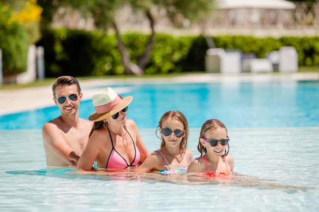 Família feliz de quatro na piscina