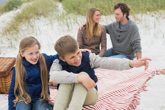 Família feliz de quatro pessoas em um piquenique de praia