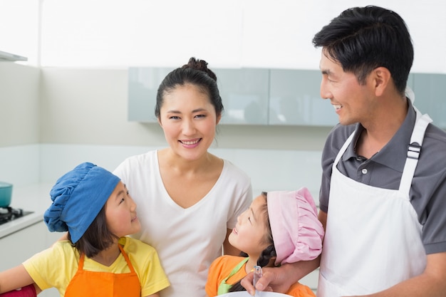 Família feliz de quatro sorrindo na cozinha