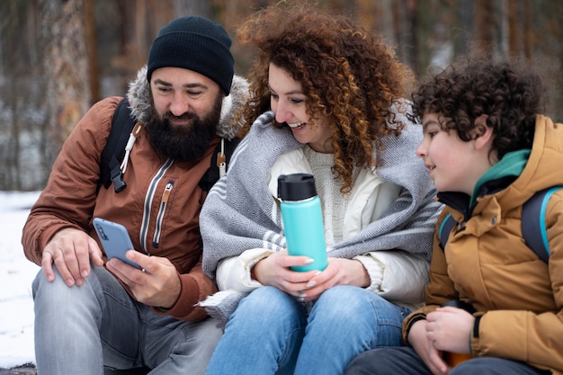 Família feliz de tiro médio olhando para o telefone