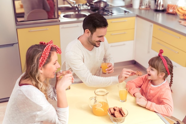 Família feliz de três tomando café da manhã na mesa