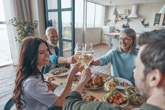 Família feliz de várias gerações brindando e sorrindo enquanto jantam juntos