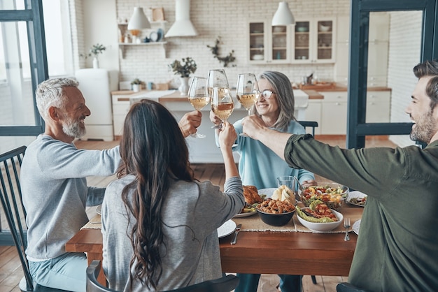 Família feliz de várias gerações brindando-se e sorrindo enquanto jantam juntos